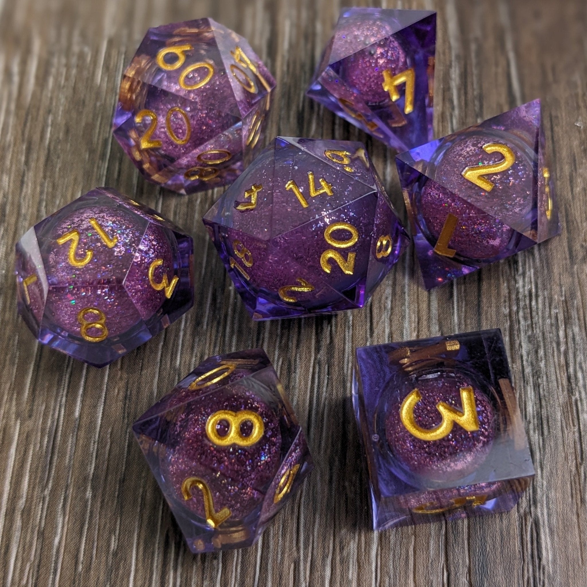 Purple liquid core dnd dice set on wooden background with gold numbers and a glitter liquid core