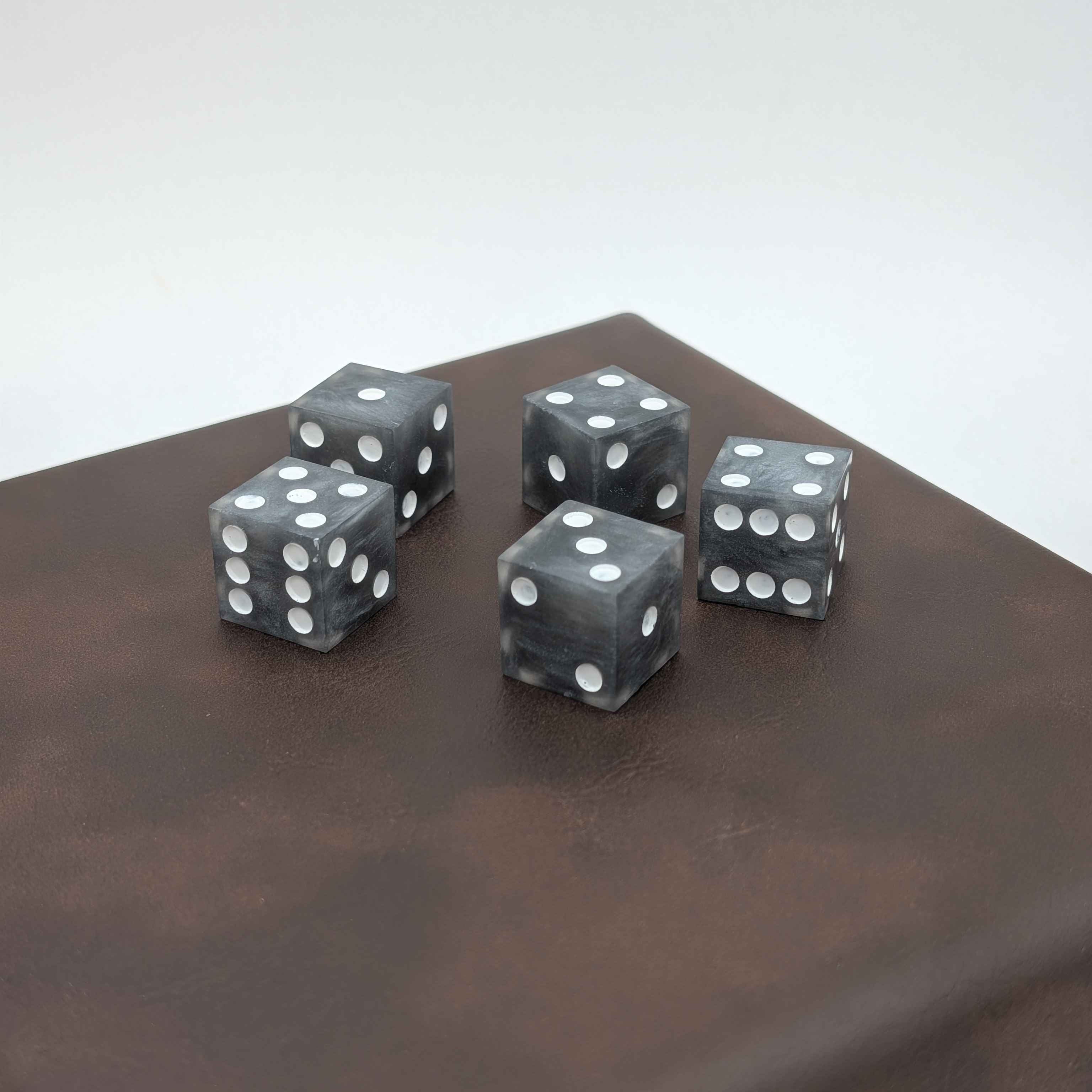 Handcrafted Grey Sharp Edge Resin Dice on Leather base and white background with painted white pips