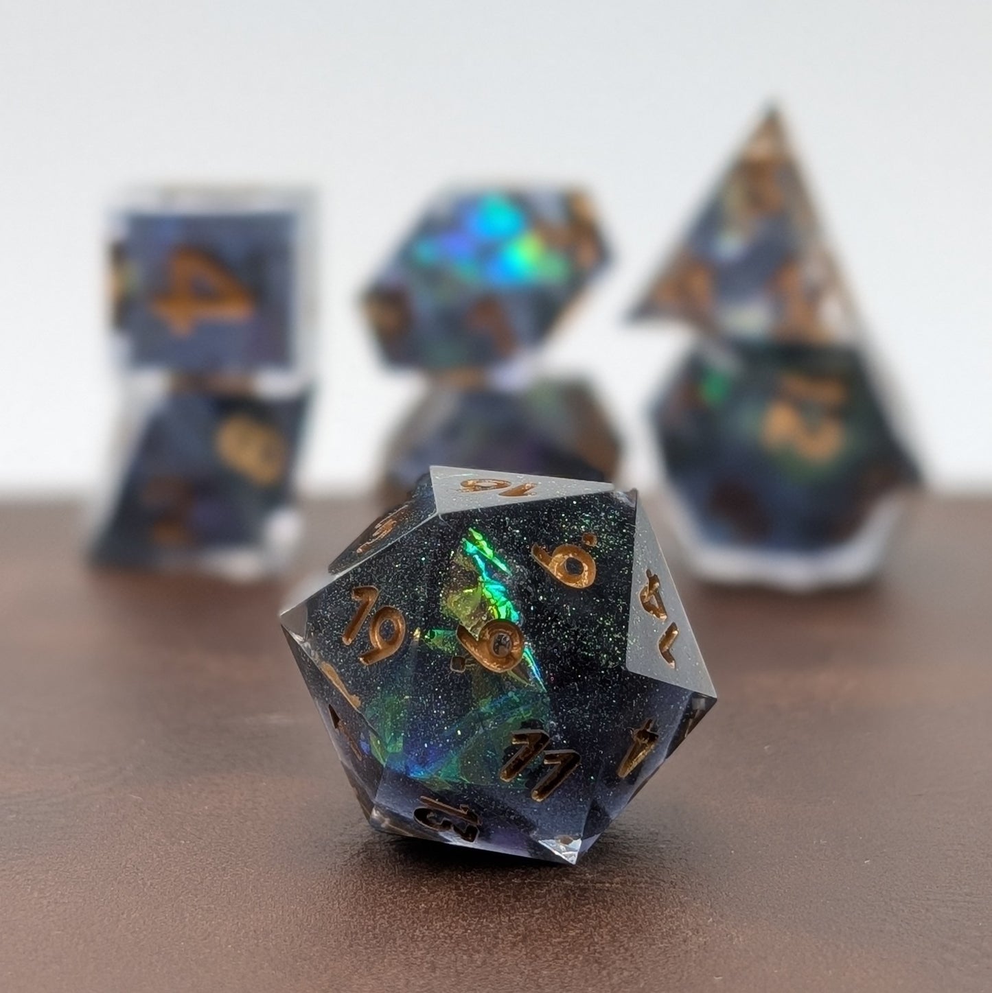Stellara D20 in front with natural boca of the other 6 dice behind on leather table.