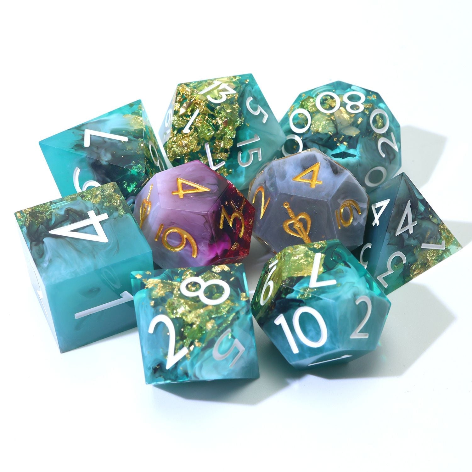 Daggerheart Dice Set on white background featuring a 7-Piece Green, black, with gold foil dice set and 2 duality dice in gold, white, pink and purple on a white background clustered.