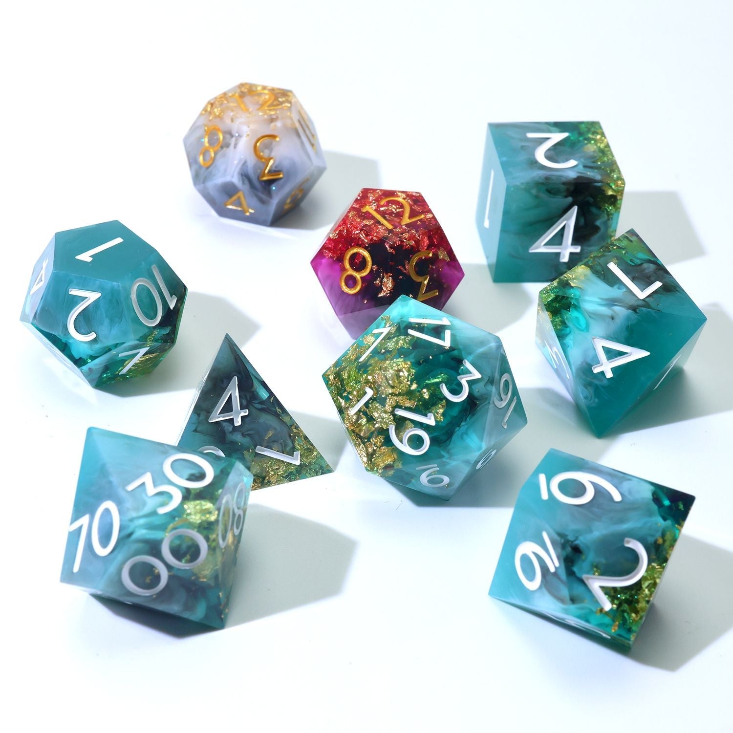Daggerheart Dice Set on white background featuring a 7-Piece Green, black, with gold foil dice set and 2 duality dice in gold, white, pink and purple on a white background spread a part with duality dice in back