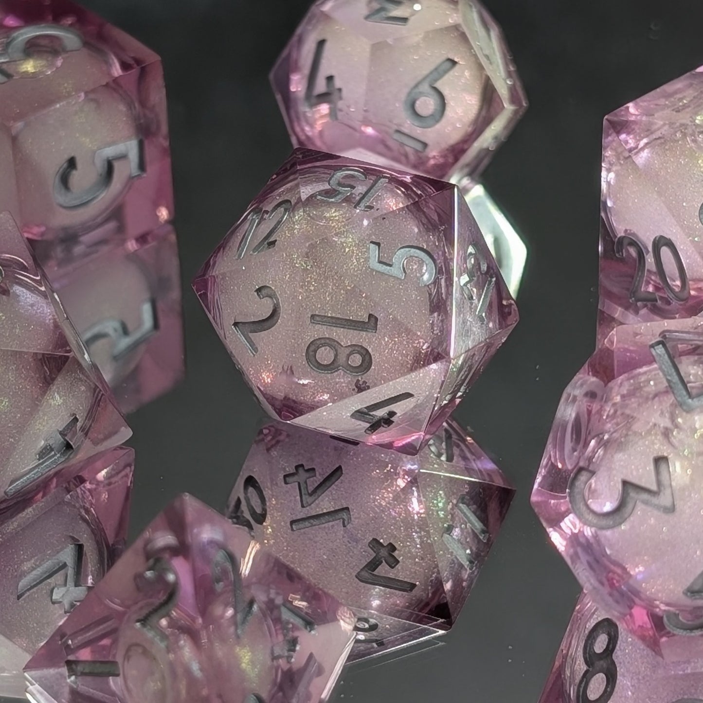 Artisan-made DND dice with pink glitter resin, a liquid-filled d20, and sleek silver numbering.