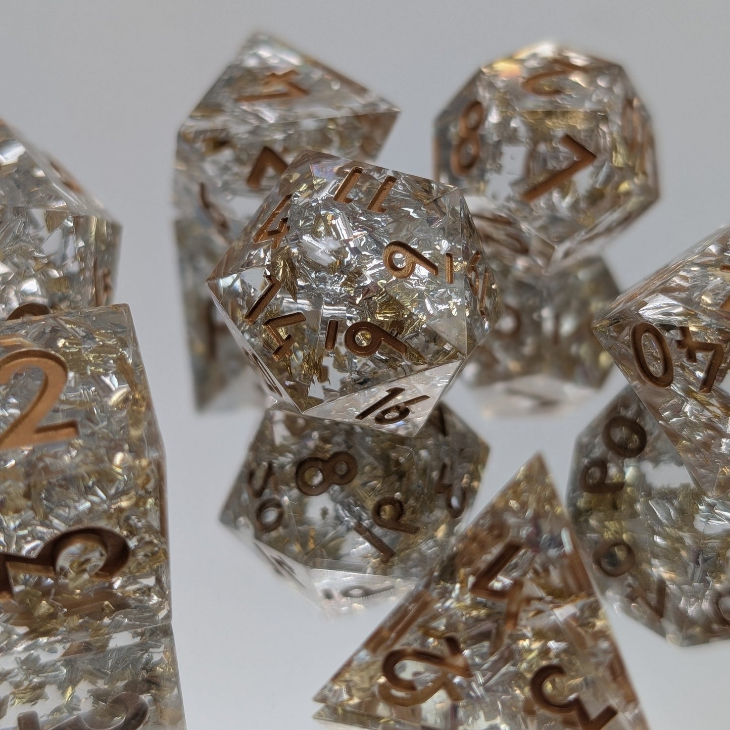 Silver and gold foil polyhedral dice set on mirror background and dark gold ink