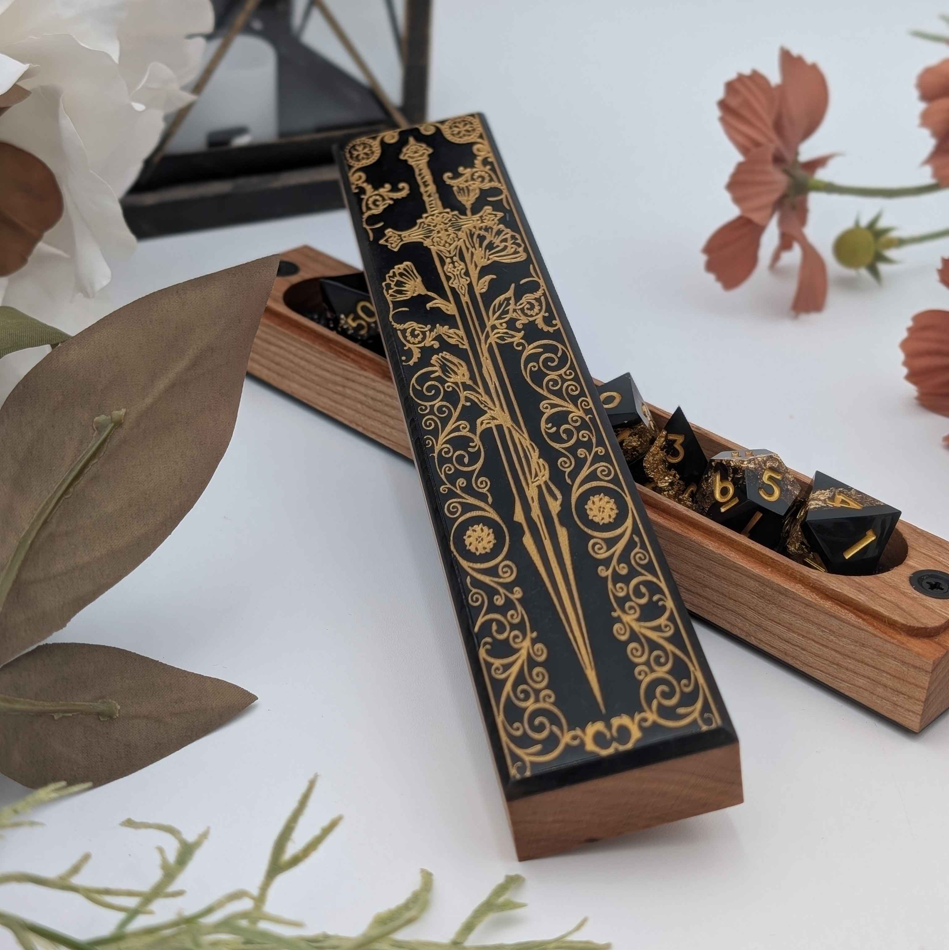 Luxury DnD dice box with black resin inlay, gold sword engraving, and magnetic closure.