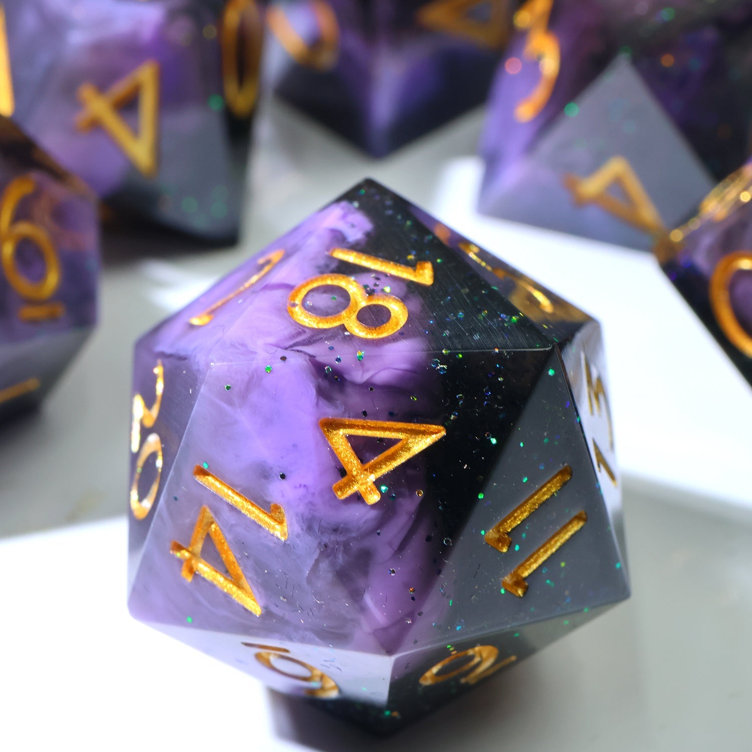 A purple and black marbled resin d20 polyhedral die with gold-colored numbers, shown in a close-up shot with other matching dice blurred in the background.
