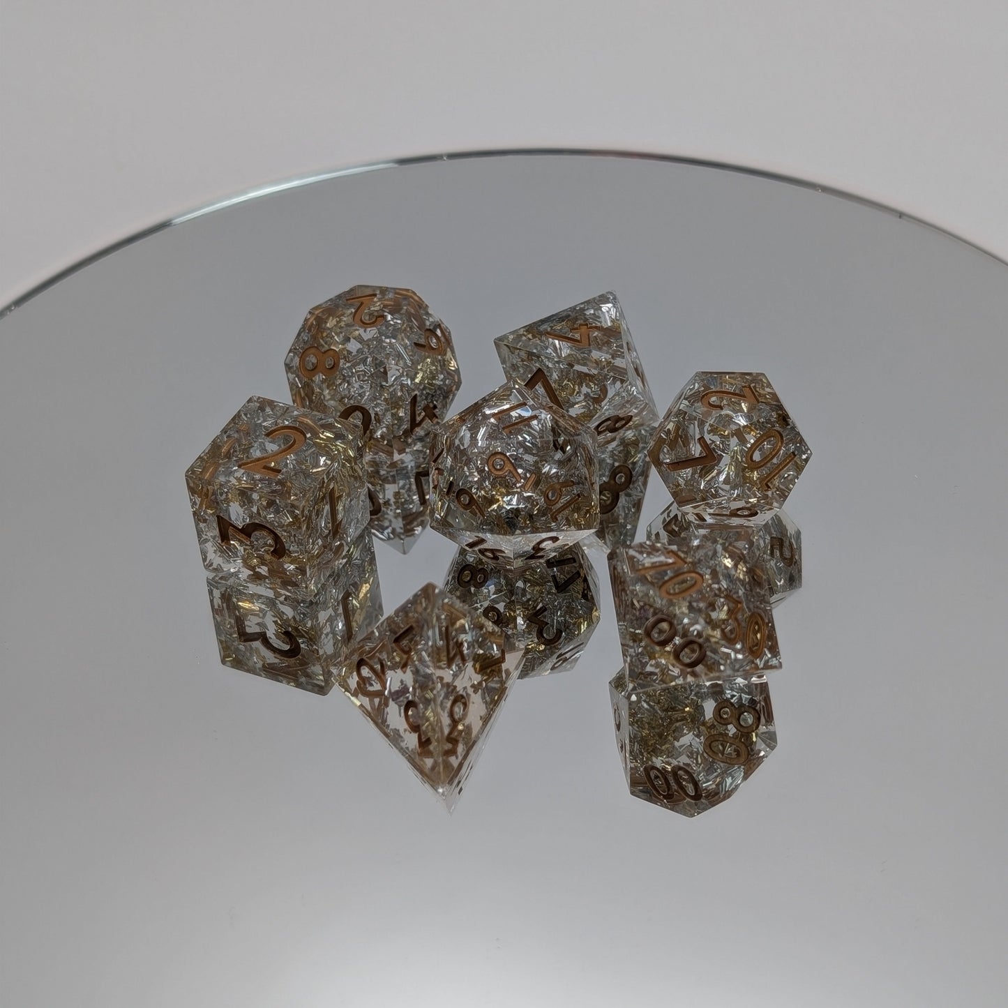 Clear resin dice with embedded metallic foil and precision-cut sharp edges on mirror base