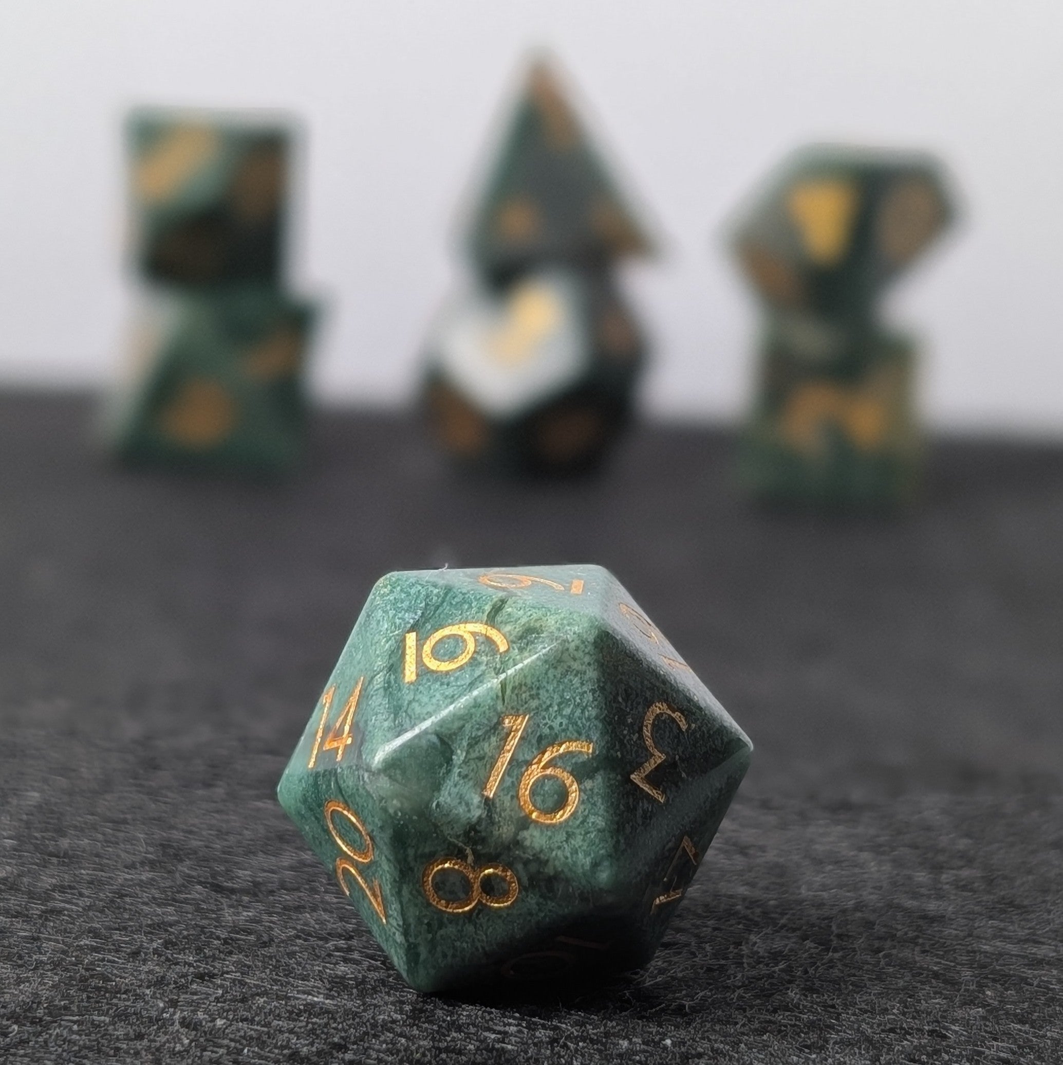 african jade gemstone dice set on a black and white background with d20 in focus with rest of polyhedral set behind