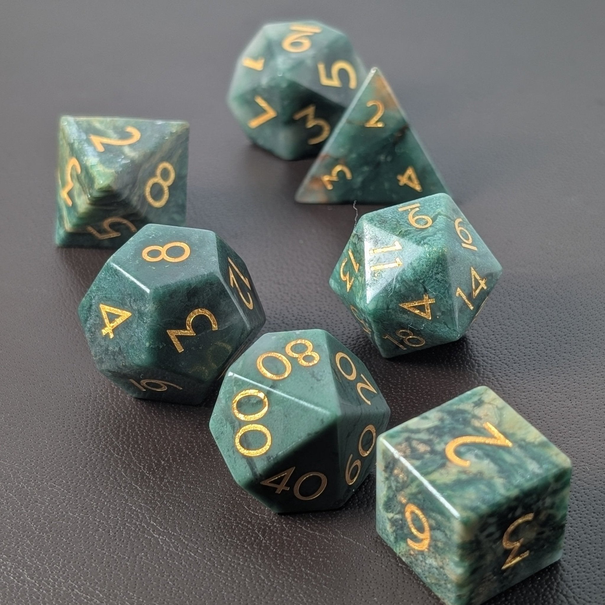 african jade green gemstone dice set on a leather background