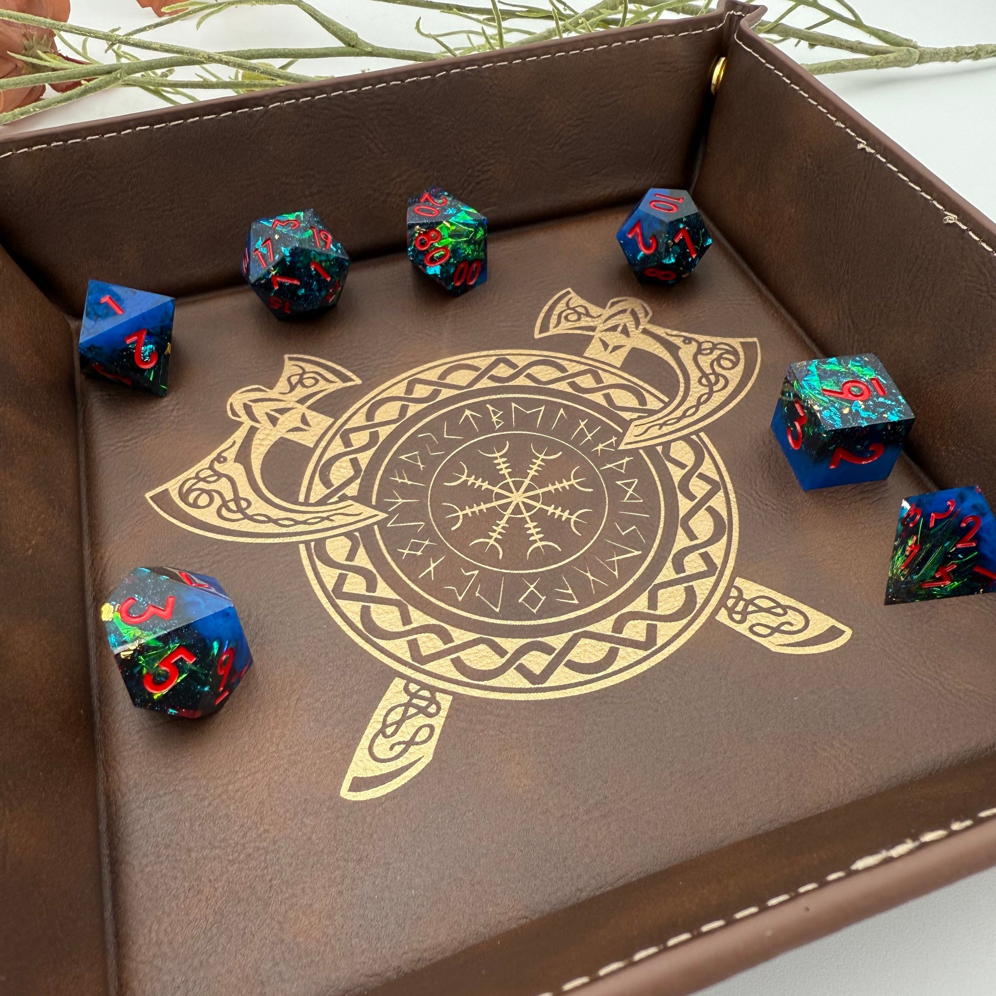 Close up of Blue Foil and Red Polyhedral DnD Dice on Brown Vegan Leather with Viking Inpsired gilded engraving