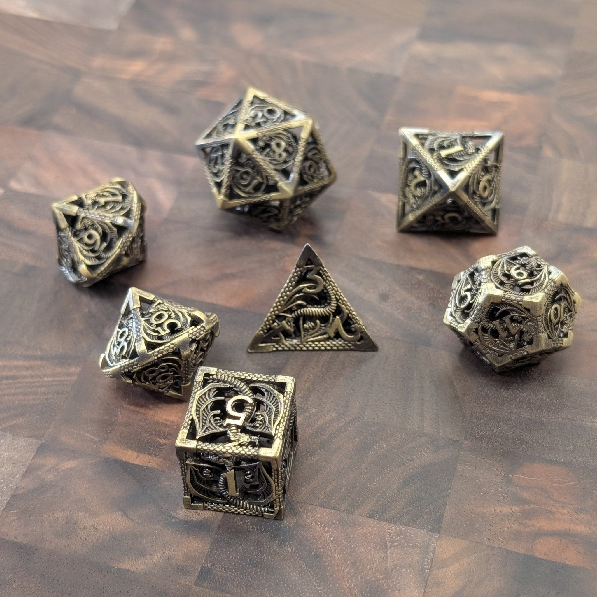 Close-up of dragon-engraved brass dice set with chime effect for TTRPGs
