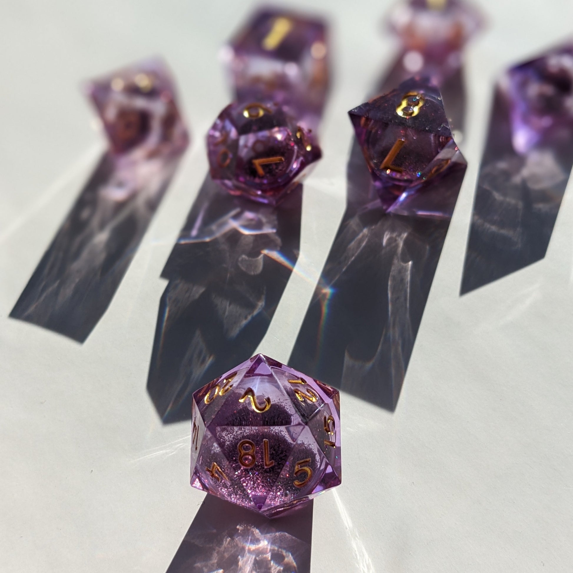 Purple and gold liquid core dice set dramatic shot with shadows