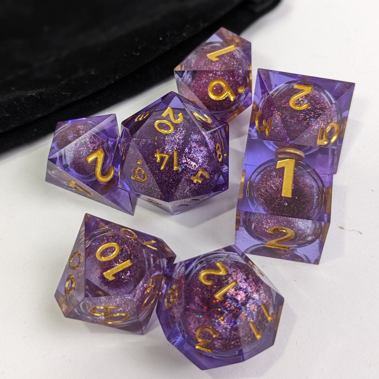 Puple Resin Liquid Core Dice Set with Gold Numbers and glitter core on white background with velvet bag