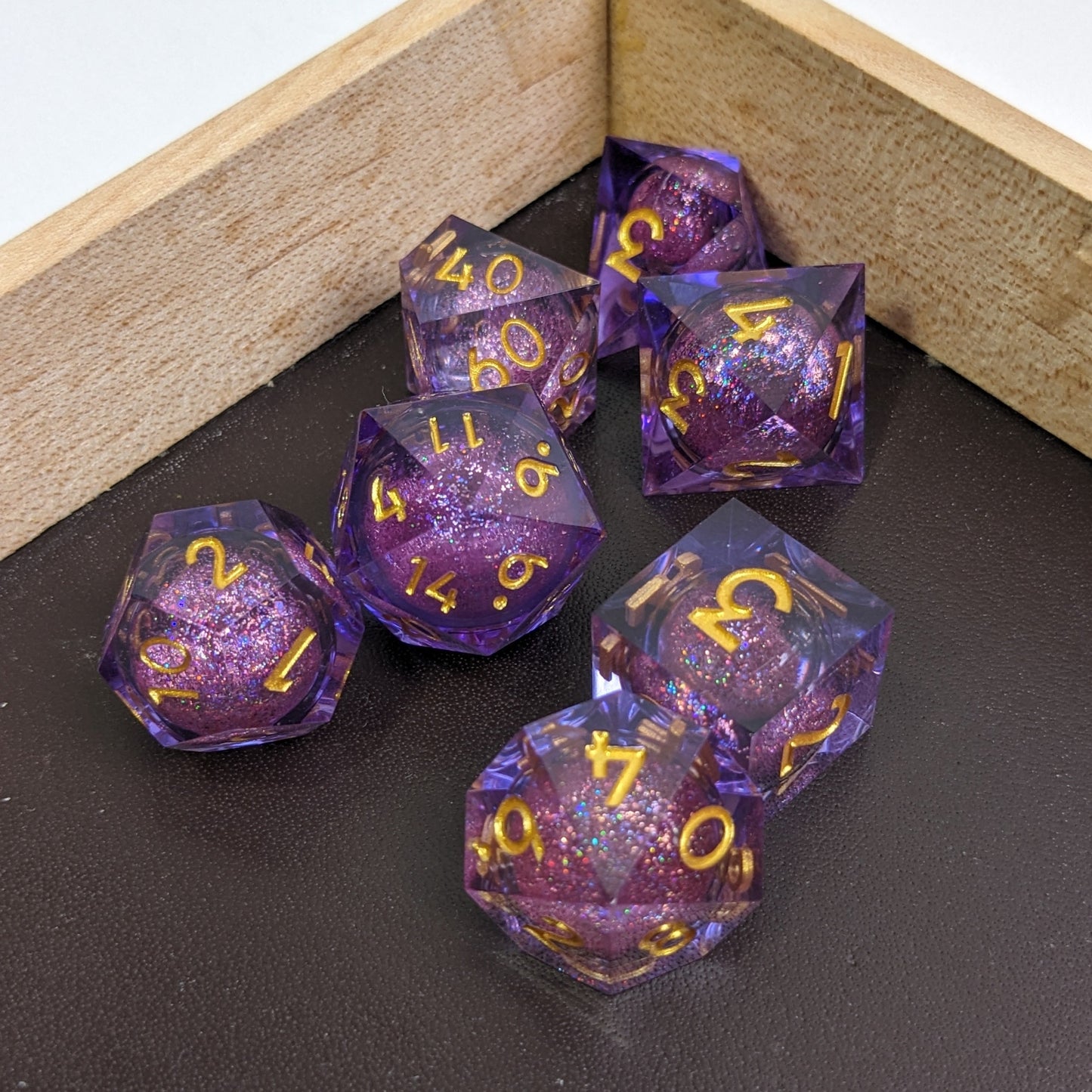 Enchanting Space DnD Dice Set in Maple Rolling Tray with Brown Leather showing off the gold numbers with purple resin in liquid core