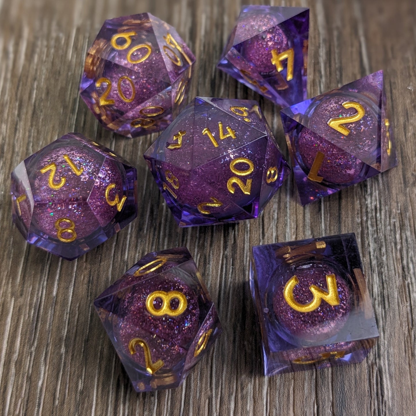 Purple liquid core dnd dice set on wooden background with gold numbers and a glitter liquid core