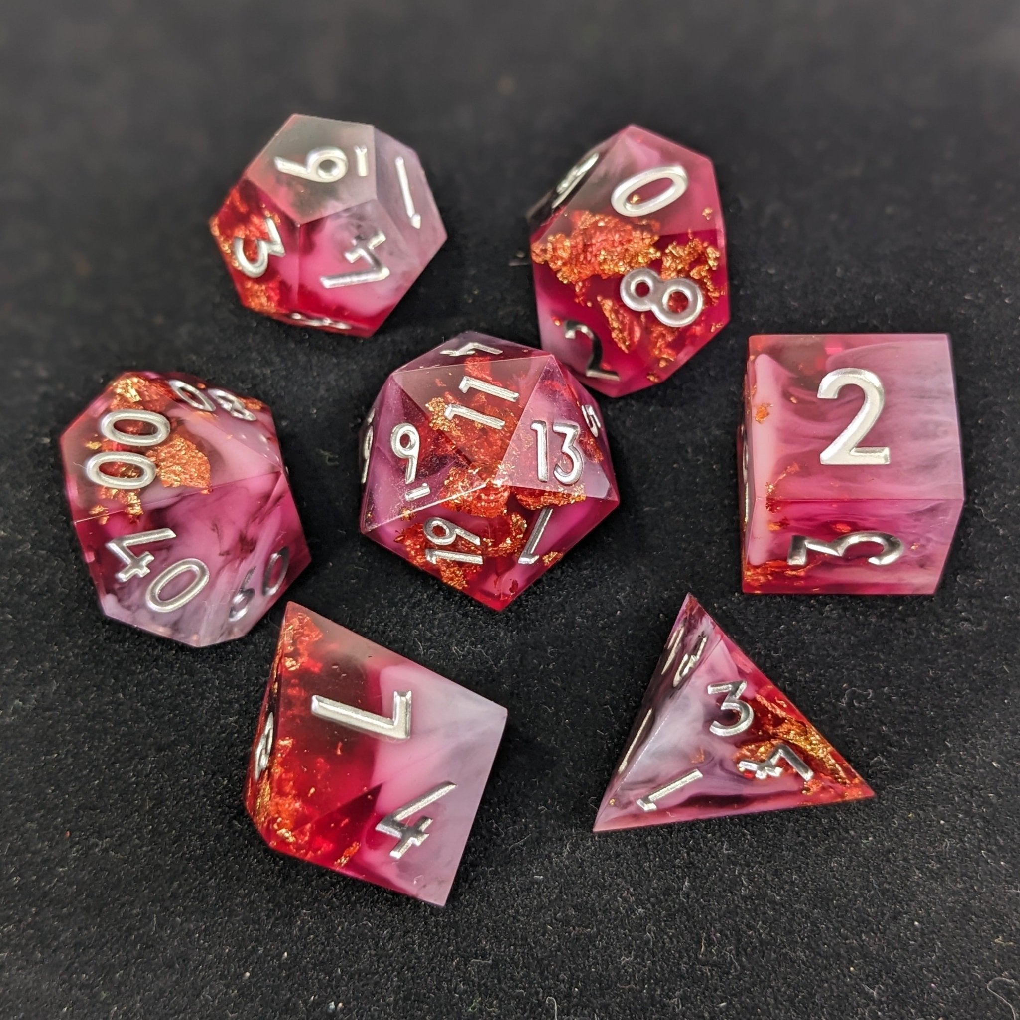 Set of pink and red dice with metallic numbers on a dark surface