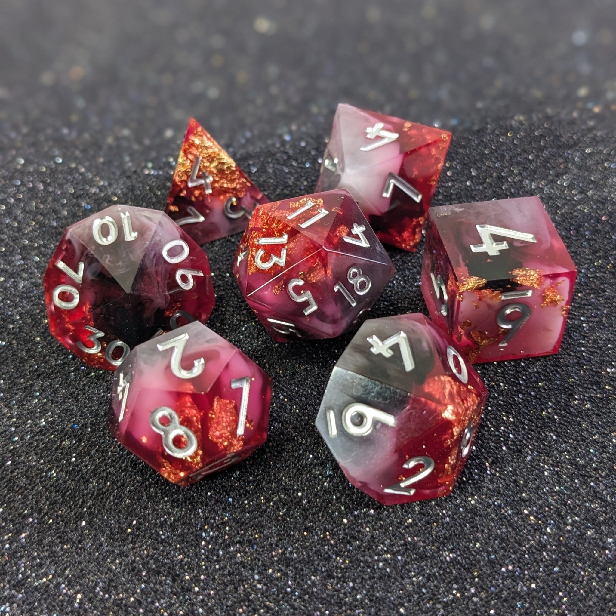 Set of red and silver polyhedral dice on a dark surface