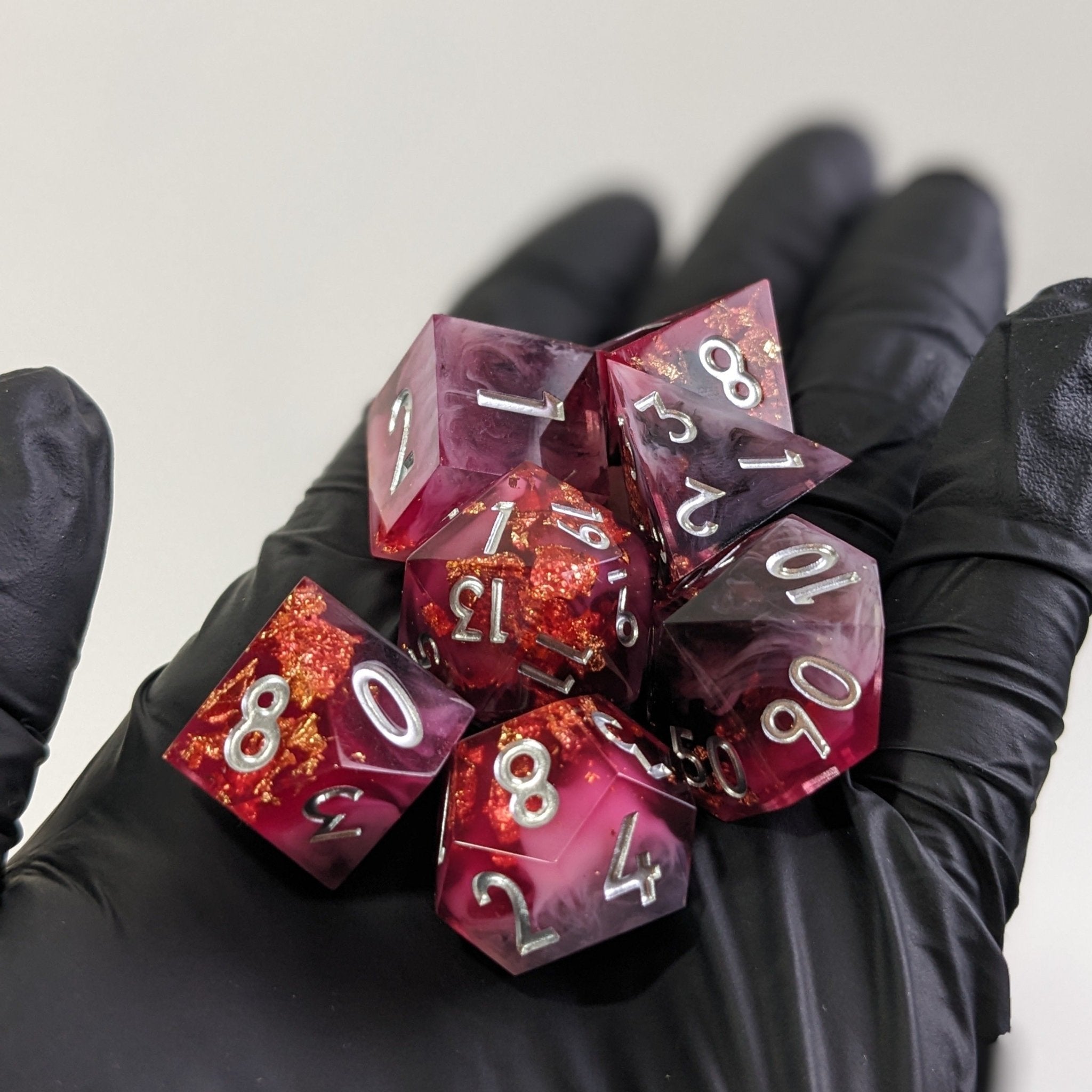 Purple polyhedral dice set held by gloved hands against a white background