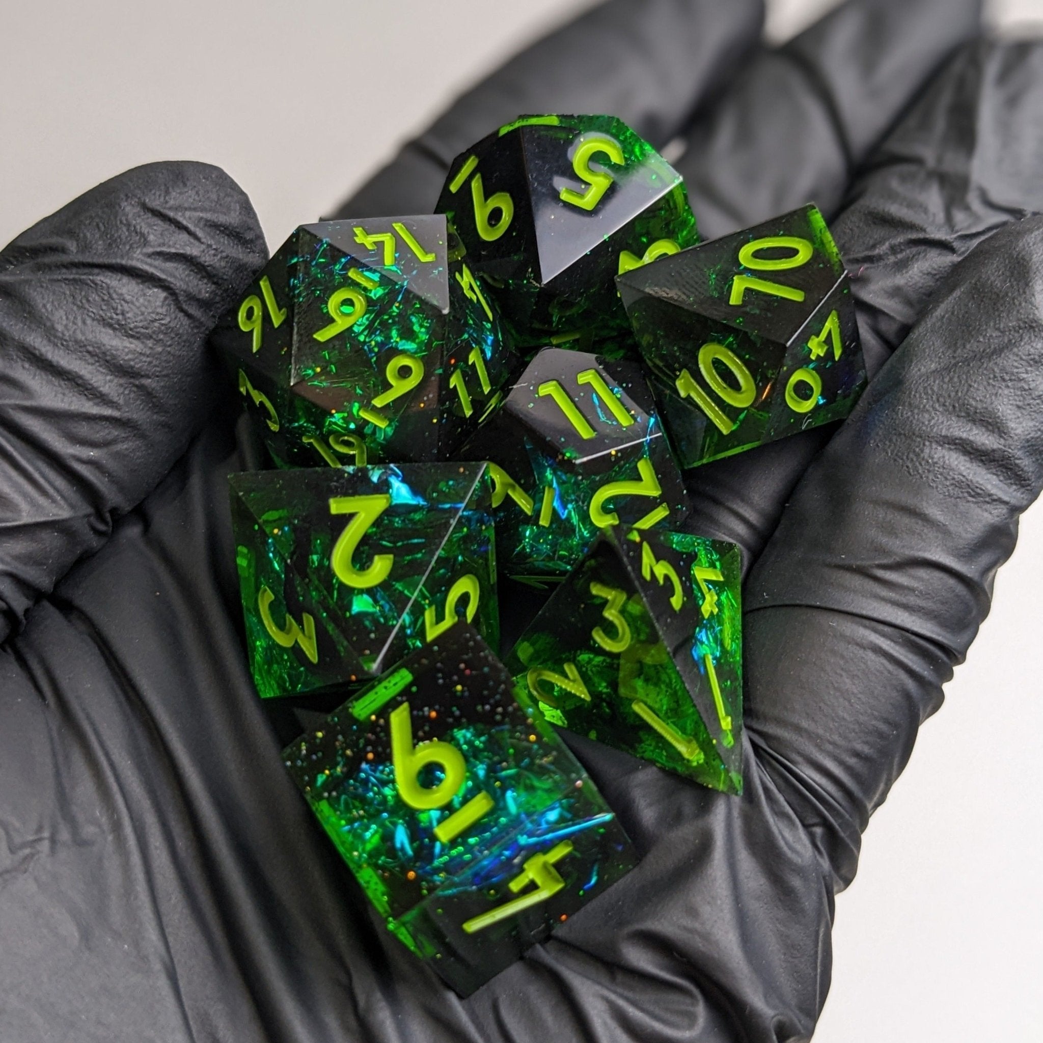 Green and black polyhedral dice set held in gloved hands
