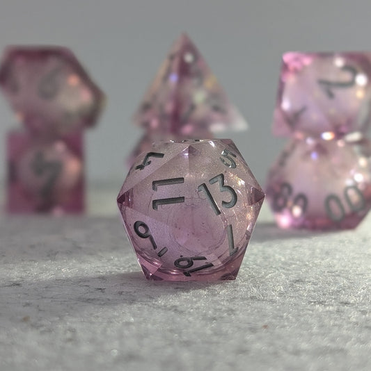 Pink liquid core dice set with sharp edges and silver ink, ideal for Dungeons & Dragons and other tabletop RPGs.