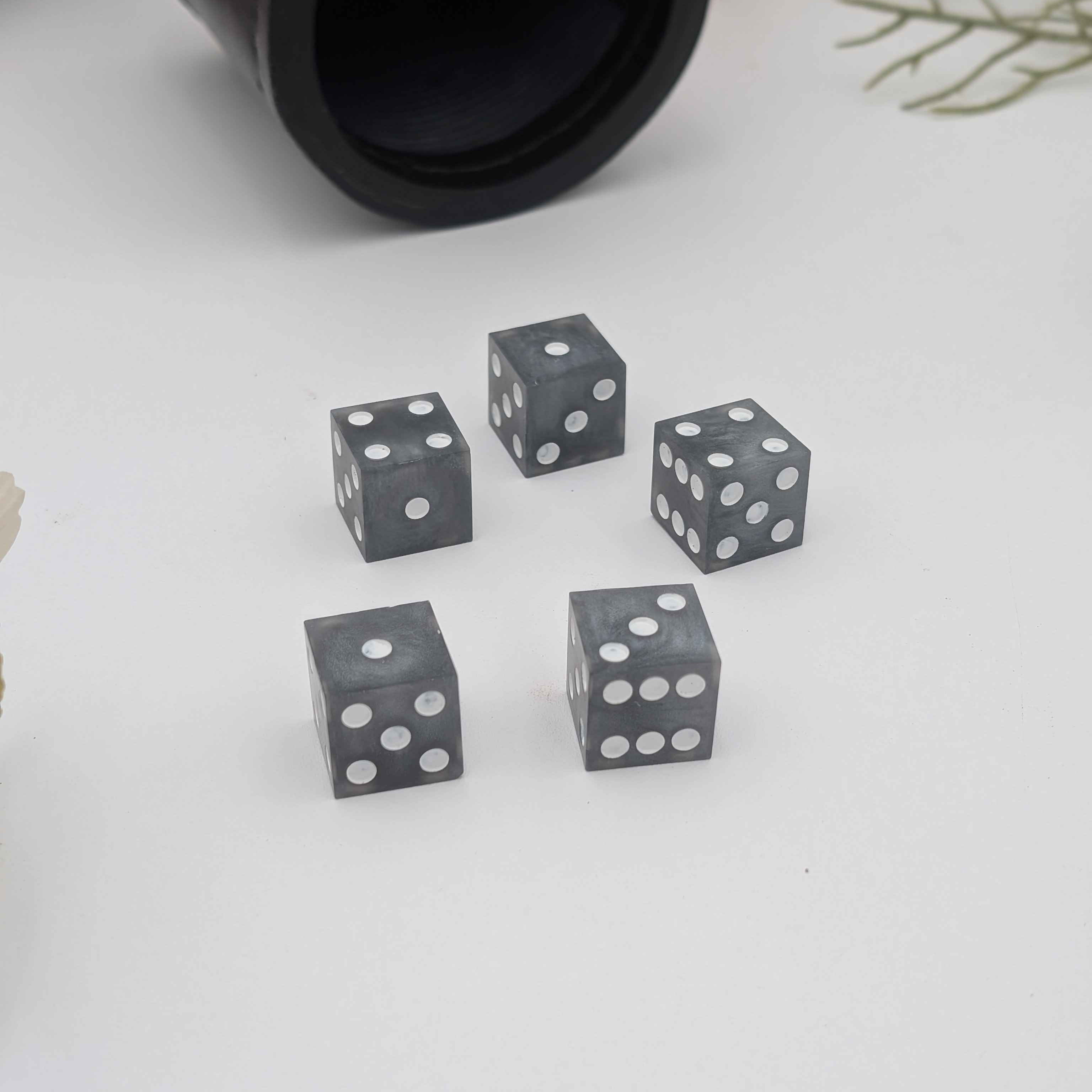 5 Grey and White Sharp Edge Resin Casino Dice on White Background with Luxury Dice Cup in background