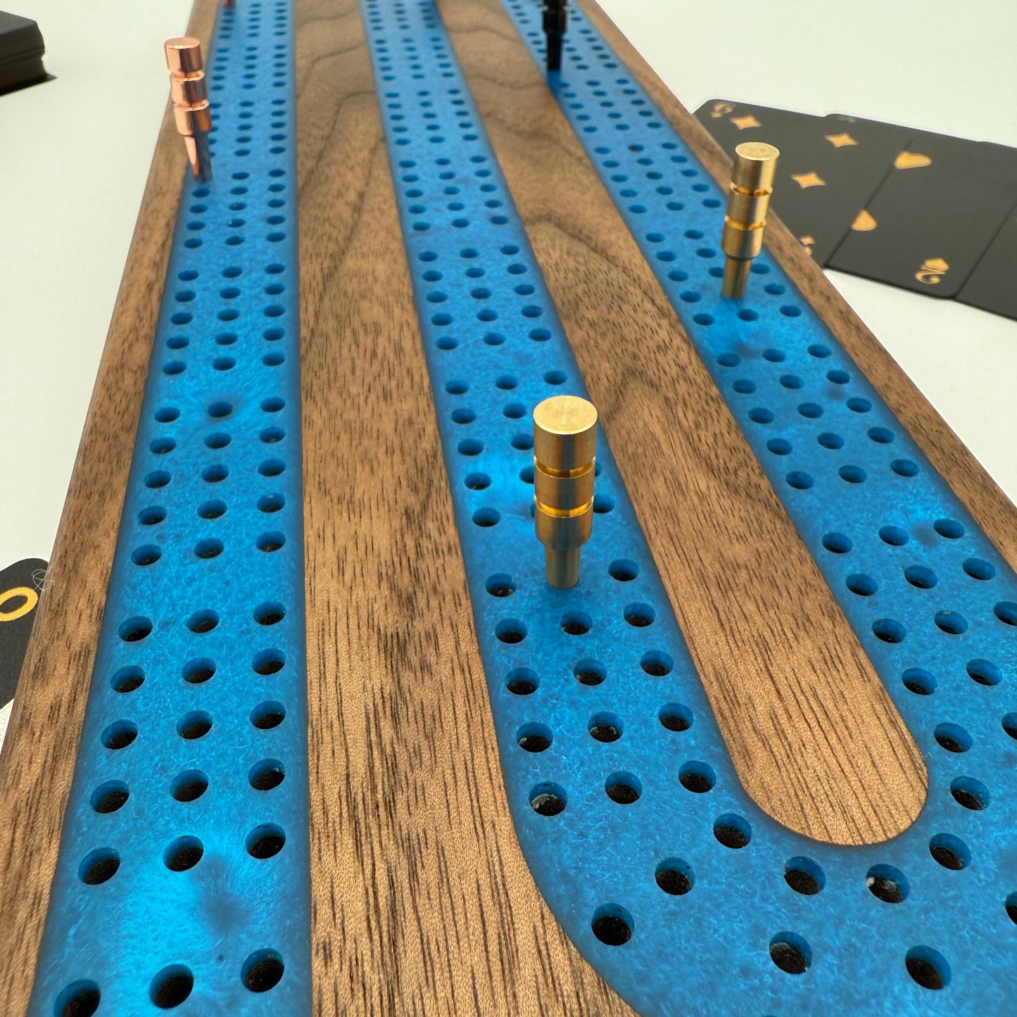 Close up handmade premium walnut cribbage board with cobalt blue resin inlay. 3 tracks