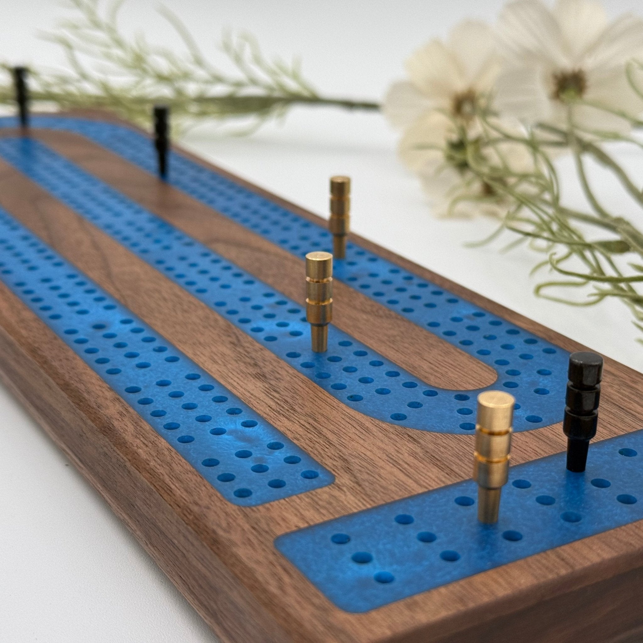 Walnut Cribbage board with blue epoxy resin inlay close up with pegs in board