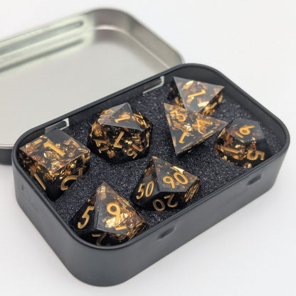 black and gold dice set with gold foil in metal dice tin on white background.