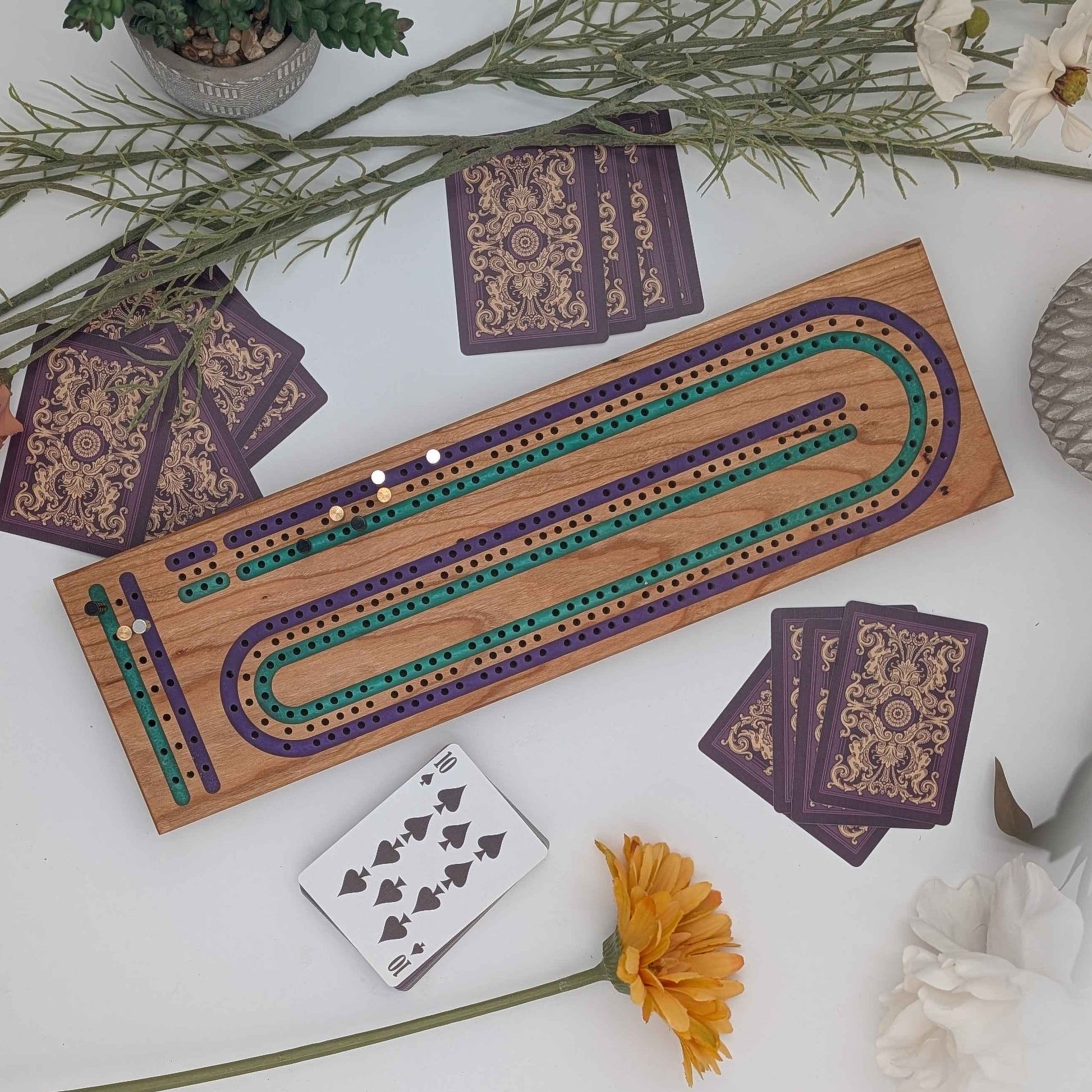 Handcrafted Cribbage board made of cherry wood featuring a 3 track resin inlay of purple and green tracks top down view