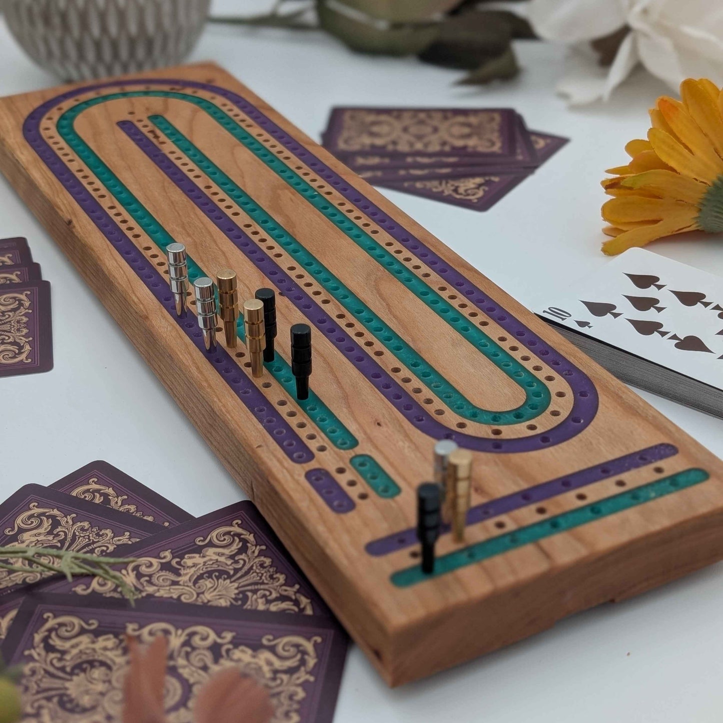 Handcrafted Cribbage board made of cherry wood featuring a 3 track resin inlay of purple and green tracks close up shot from front of board