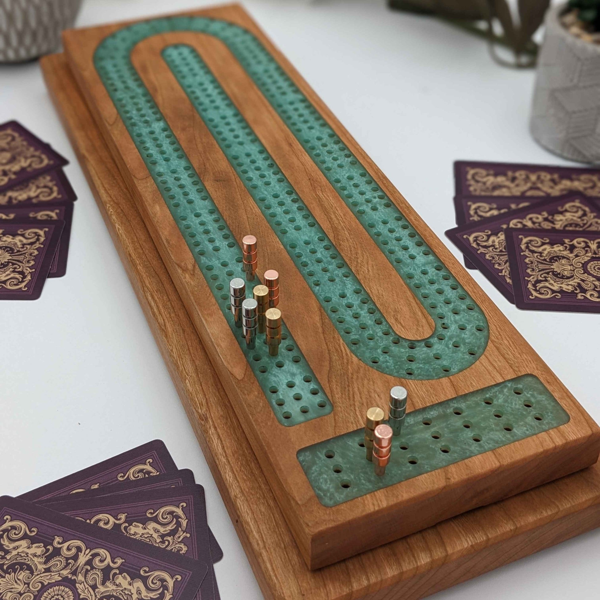 premium cribbage board made of cherry wood and resin on white background with metal pegs