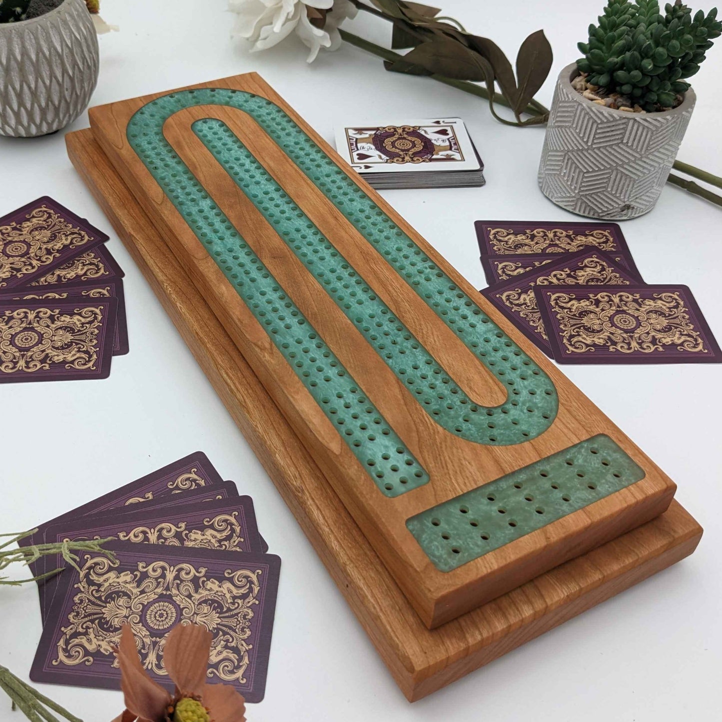 handmade cribbage board made of cherry wood on white background with cards on the table without any pegs