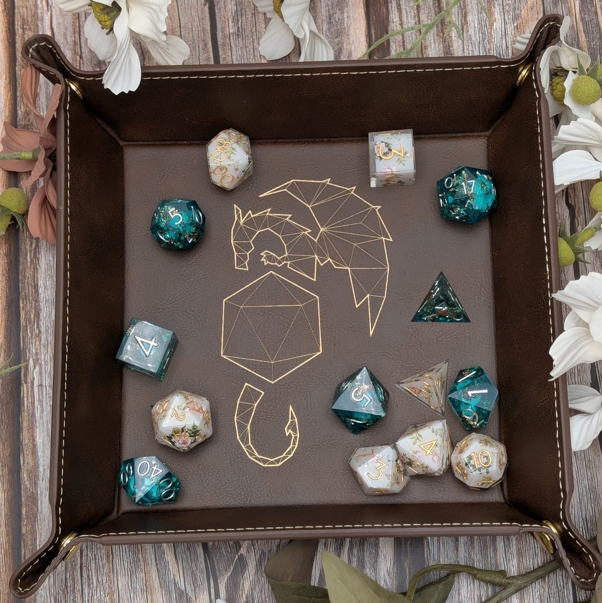 Dice tray with geometric designs on brown leather surrounded by flowers.