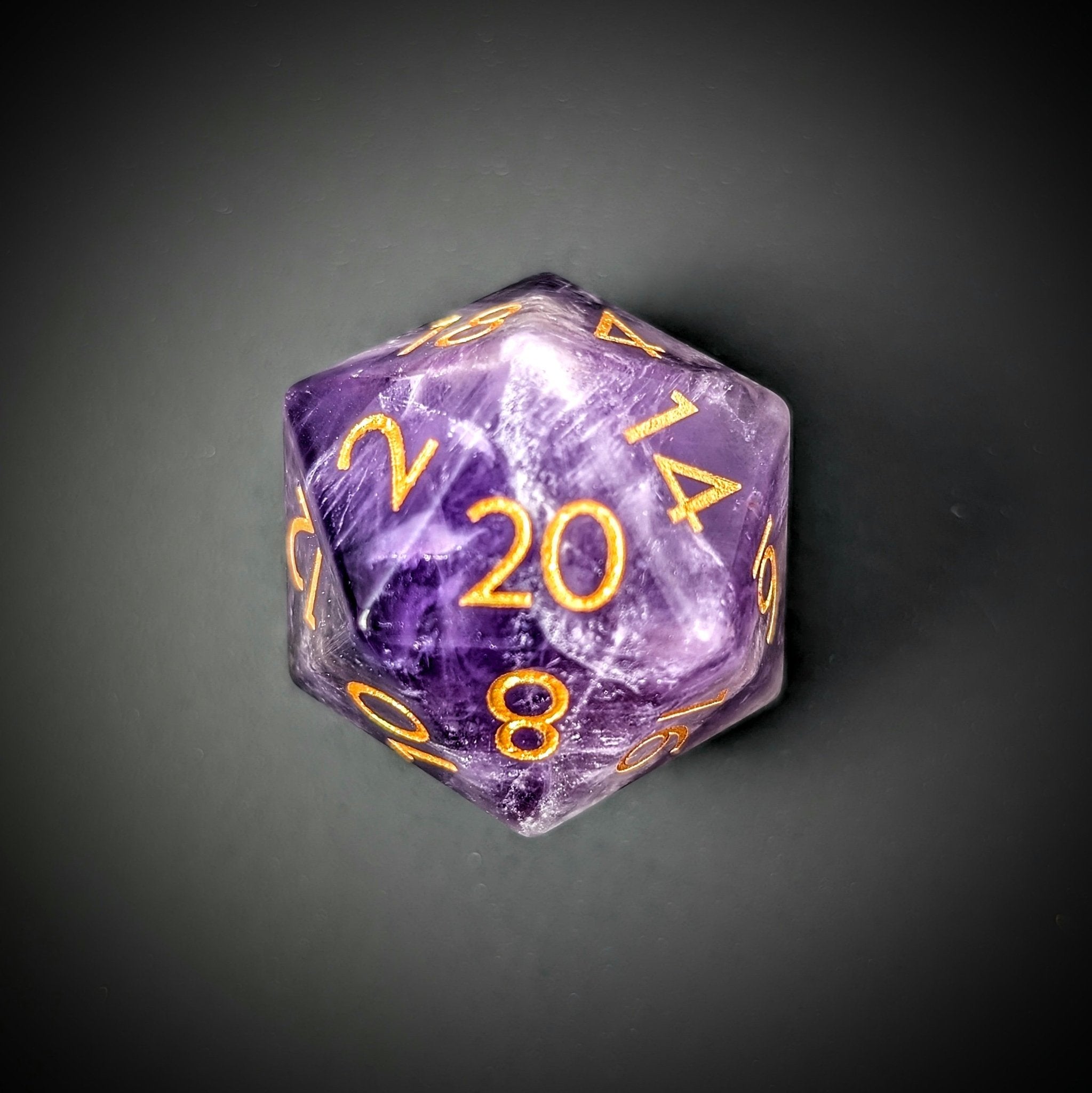 Single Ebonwood Amethyst D20 dice on a sleek black background, highlighting its unique purple gemstone clarity, natural striations, and elegant minimalist gold-inked font.