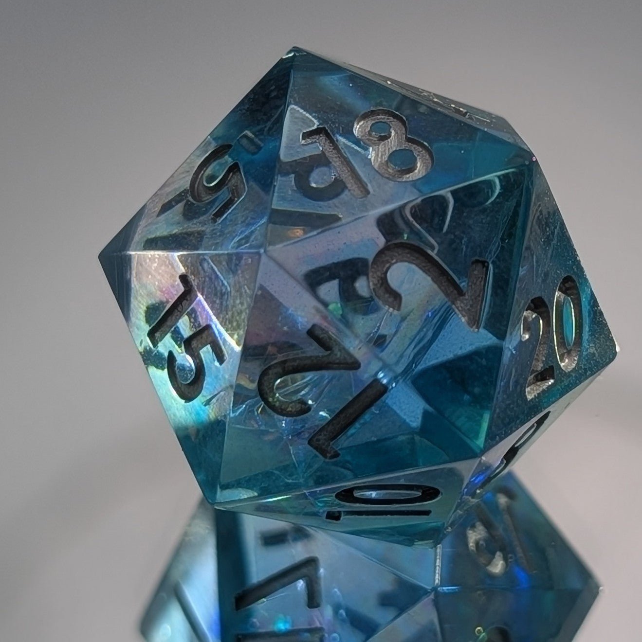 Close up of a blue & iridescent d20 on a mirror base