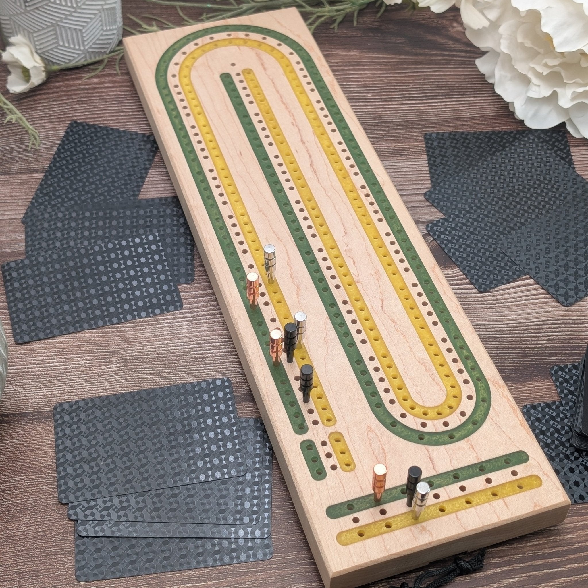 Maple cribbage board with green and gold lanes on brown background