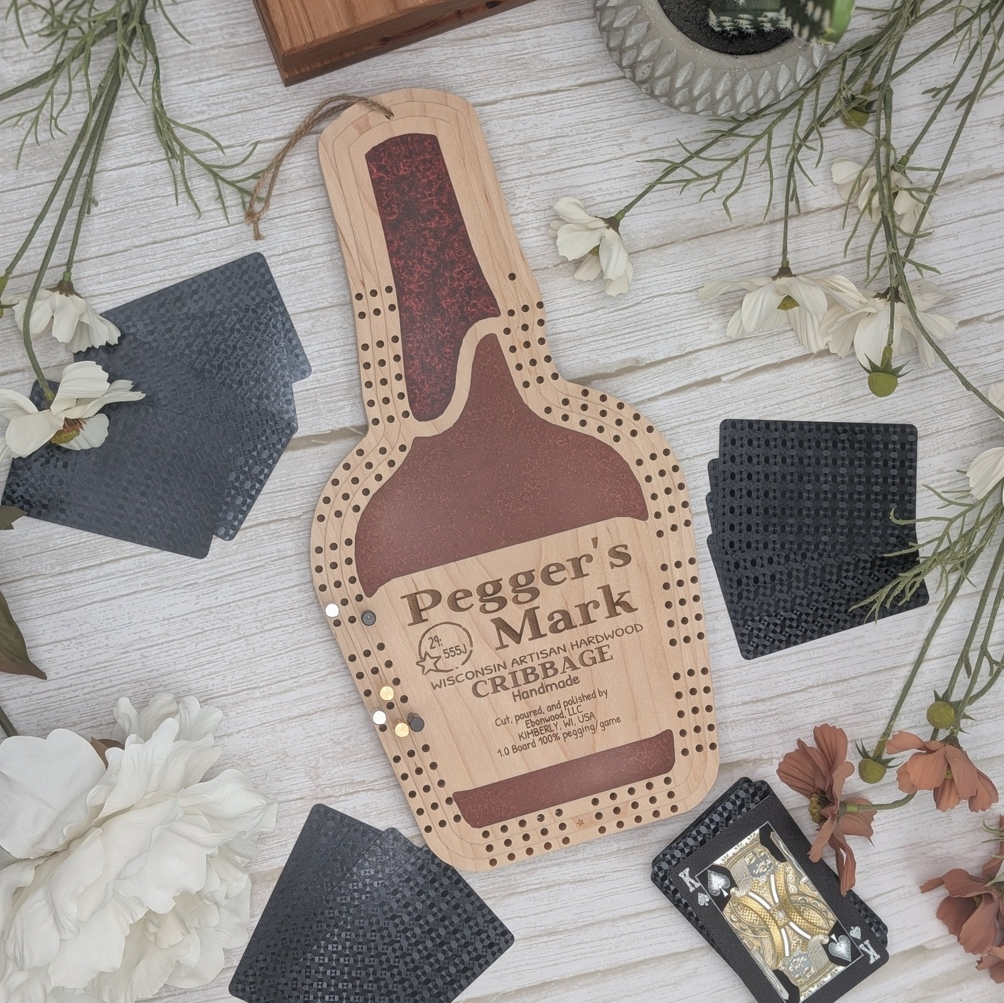Cribbage board with 'Pegger's Mark' branding on a wooden surface with decorative elements.
