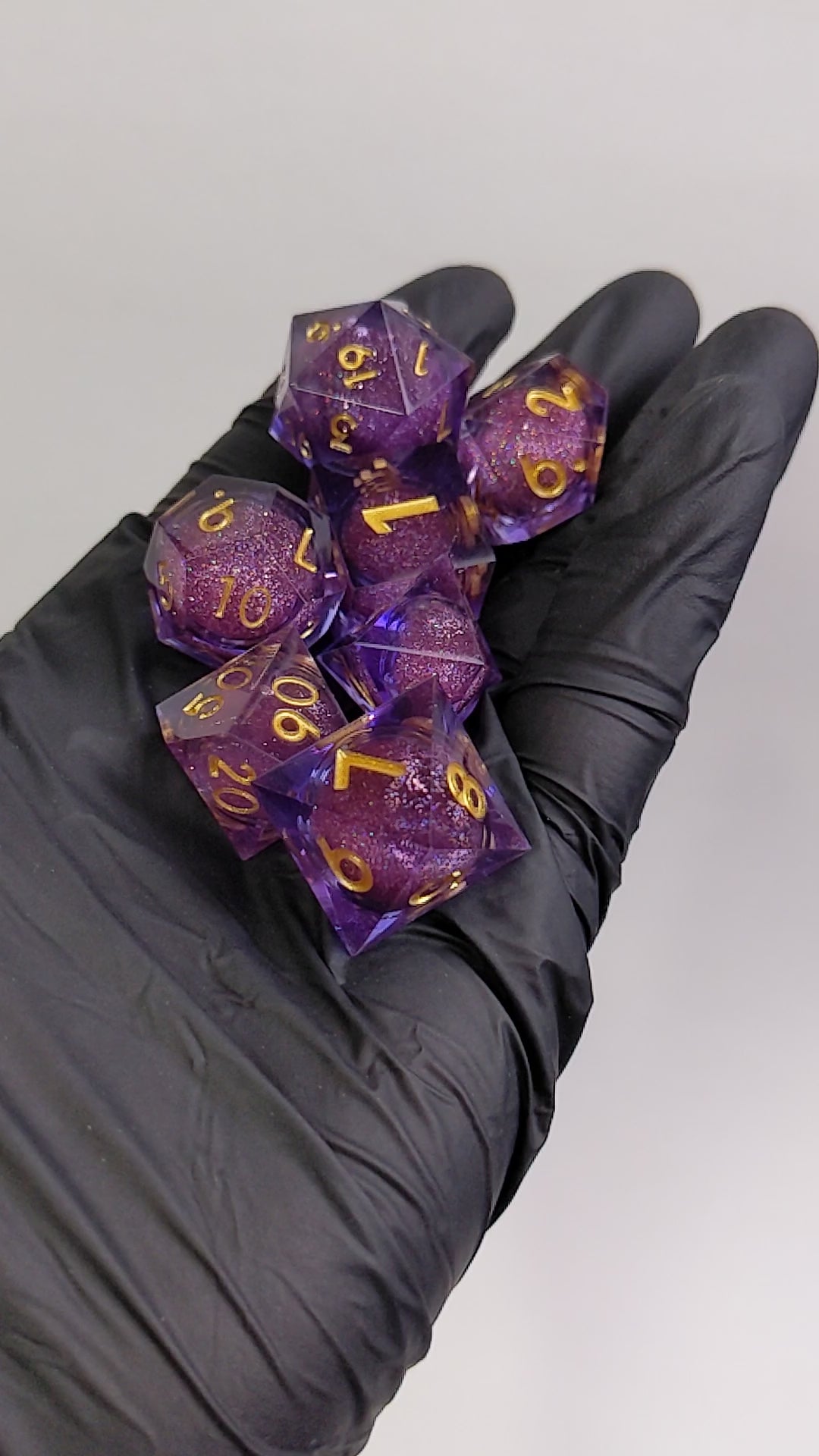 Liquid core dice set shaken in hands, dice set is purple sharp edge resin with gold numbers