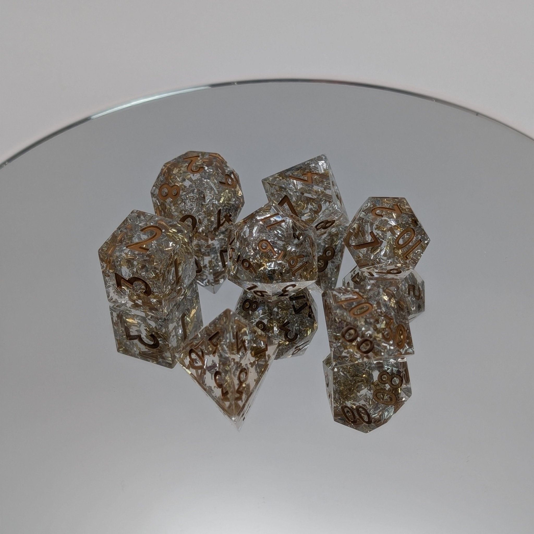 Clear resin dice with embedded metallic foil and precision-cut sharp edges on mirror base
