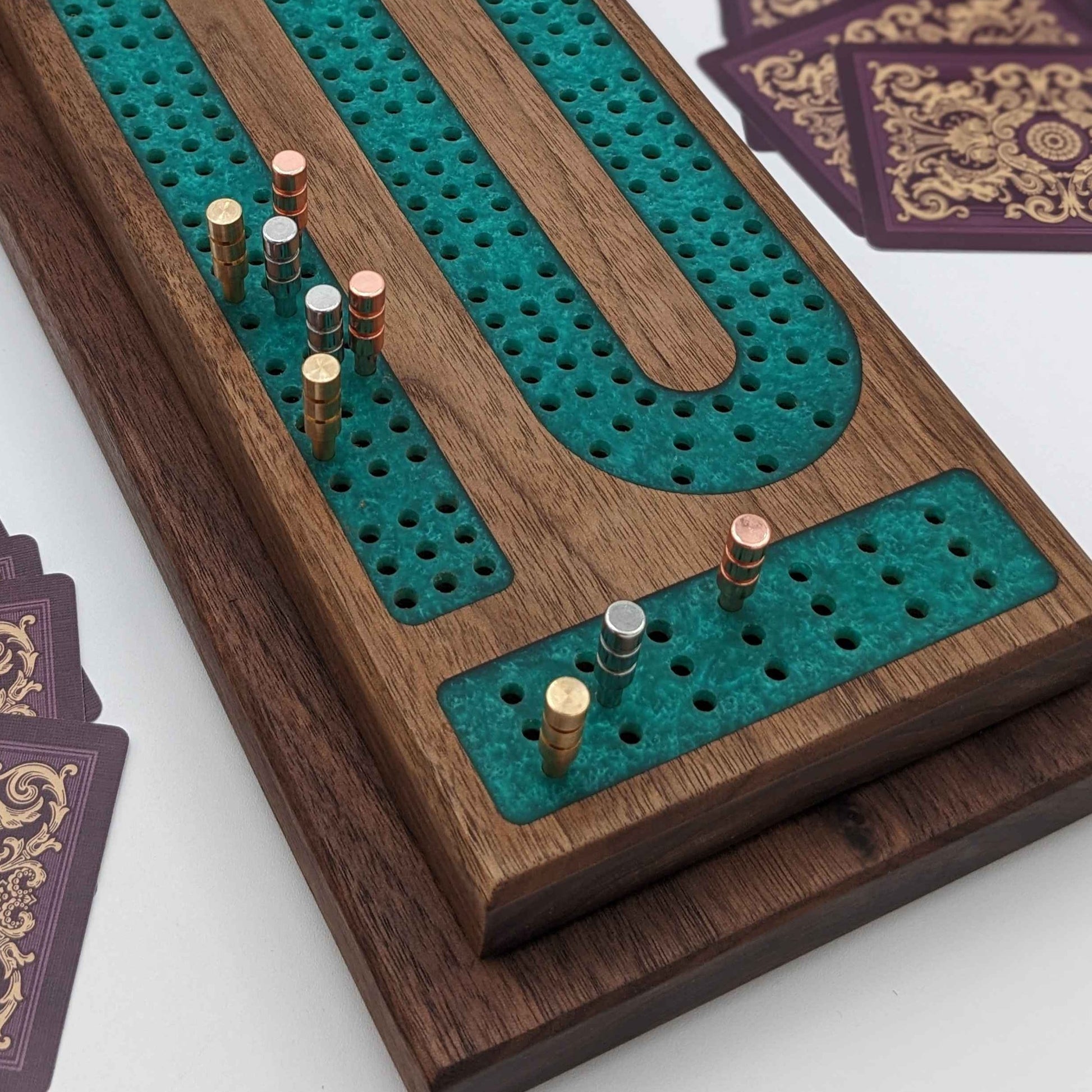 handmade walnut cribbage board with emerald epoxy resin inlay with card and page storage side view on white background