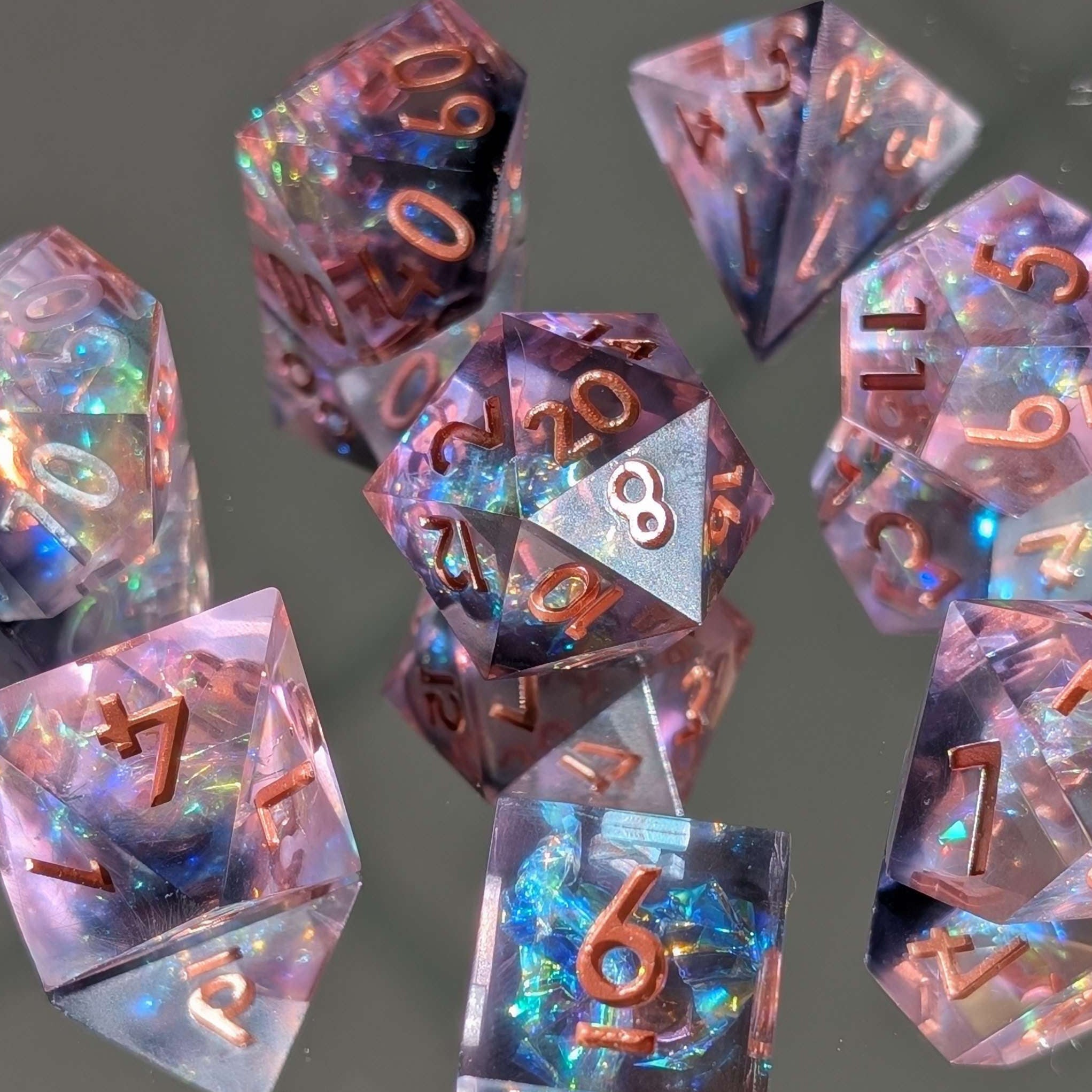 A collection of sharp edge resin dice with pink resin and metallic copper numbers, featuring color-shifting mylar flakes and a hand-poured design.