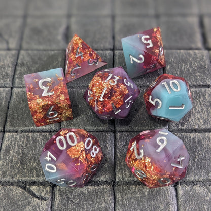 Blue, Purple, and pink sharp edge polyhedral dice set on grey background